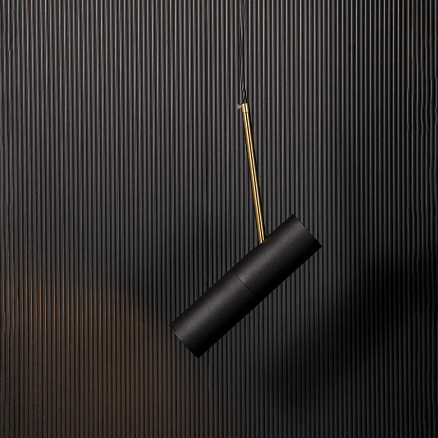 Modern black cylindrical pendant lamp glowing with warm light golden accent stylish ceiling fixture for luxury home interiors.