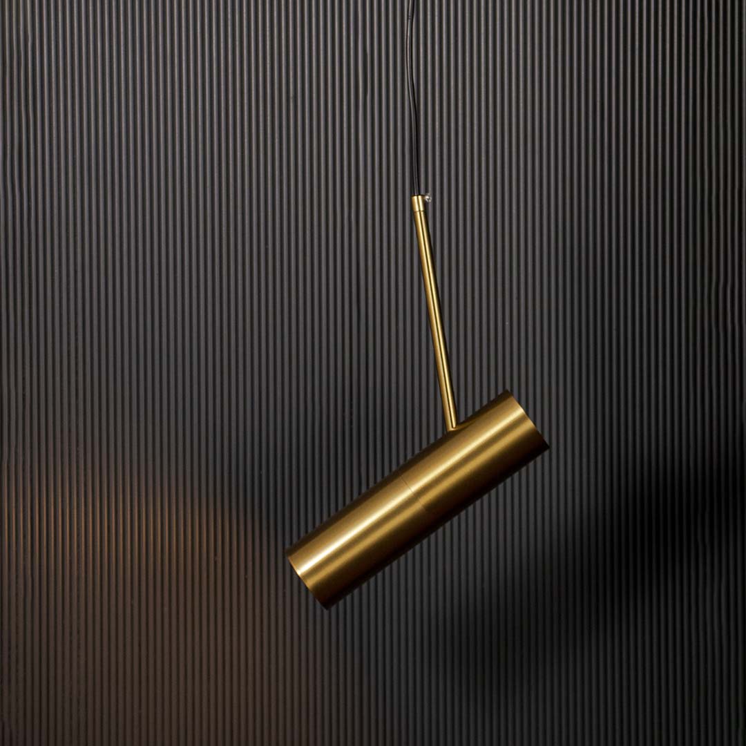Contemporary gold cylindrical pendant lamp glowing with warm light sleek ceiling fixture for luxury modern home decoration.