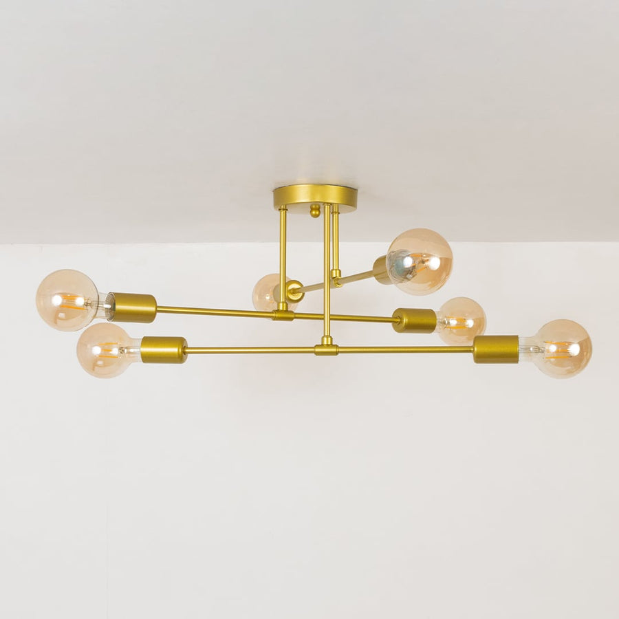 Gold chandelier displayed against a white background with lights off highlighting its minimal elegant metal frame and design