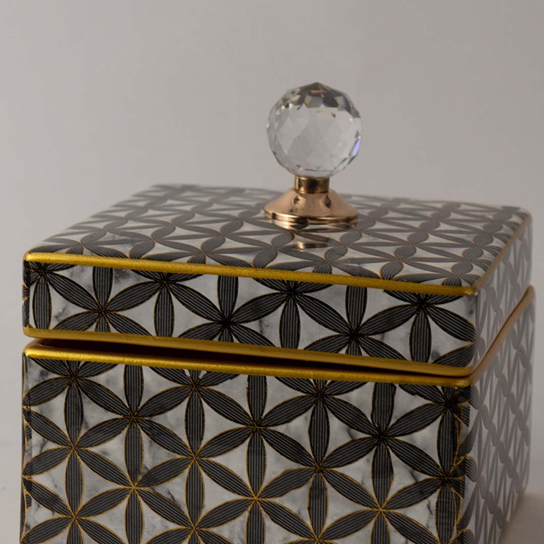 Closeup of black geometric ceramic decor jar showing fine gold detailing and elegant crystal knob on the lid.