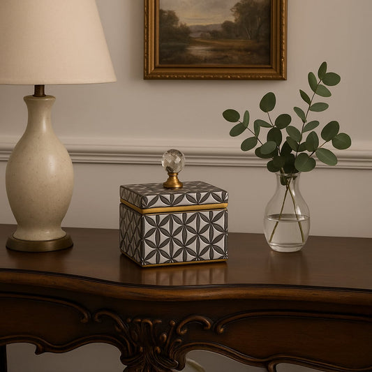 Small black and gold ceramic jar with crystal knob lid styled on table adding modern luxury accent to home decor.