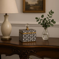 Small black and gold ceramic jar with crystal knob lid styled on table adding modern luxury accent to home decor.