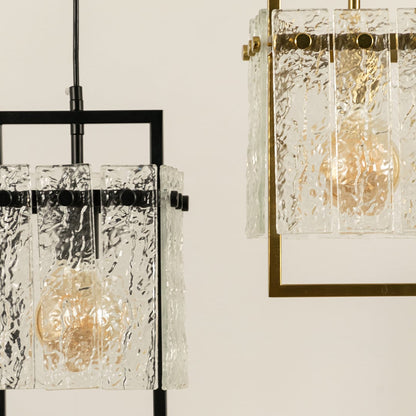 Close view of a pendant light with a textured glass shade and black metal frame showing warm illumination through the detailed glass that adds a refined modern accent to the room.