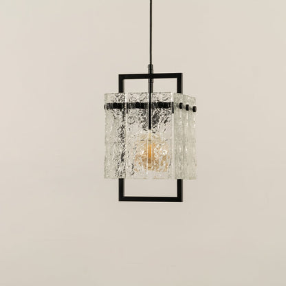 Pendant light with a textured glass shade framed in black metal glowing warmly and creating an elegant patterned illumination that adds a refined modern accent to the interior.