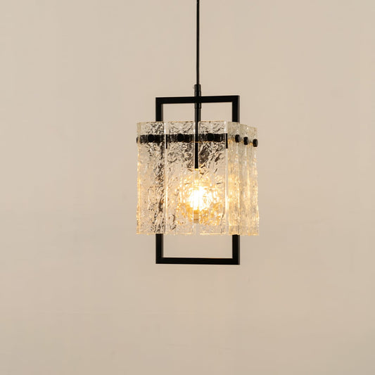 Decorative pendant light with a detailed glass shade and dark frame hanging from the ceiling casting a warm patterned glow that enhances the surrounding interior space.