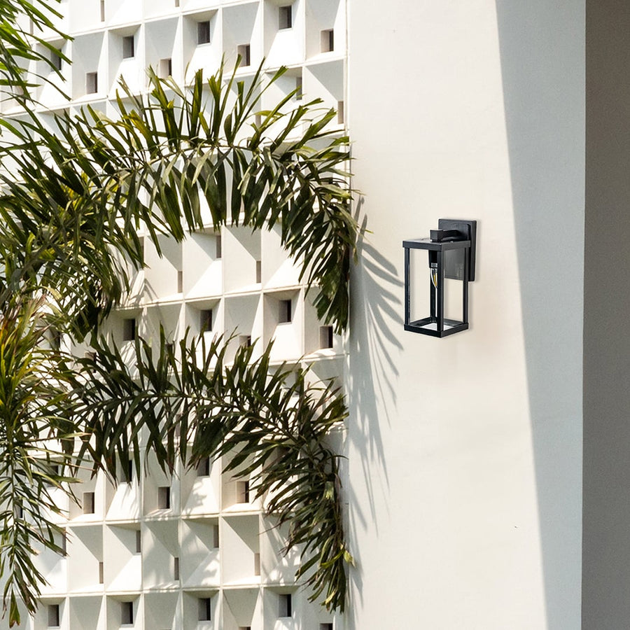 Modern outdoor wall light with black frame and glass shade illuminating exterior beige wall for stylish home lighting.