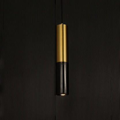 Black marble and metal cylinder pendant light hanging against dark textured wall with light off for bold modern décor.