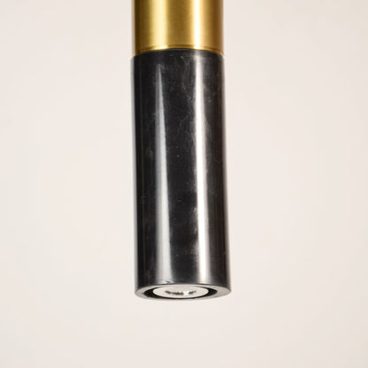 Black marble and metal long cylinder pendant light shown in close up view with light off for sophisticated modern décor.