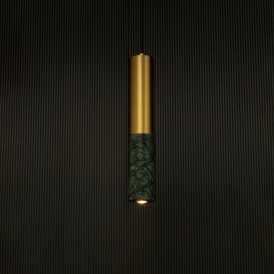 Green marble and metal cylinder pendant light hanging against dark textured wall with light off for stylish luxury décor.