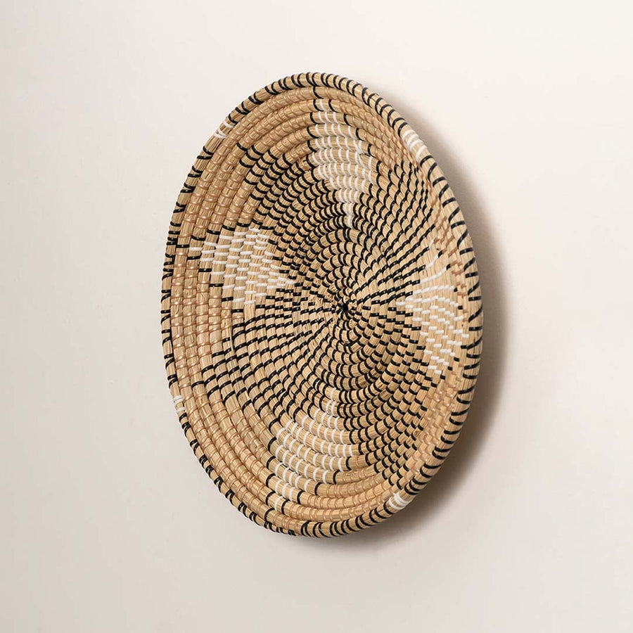 Side profile of the flat woven wall basket showing the natural fiber texture and sturdy rim design on a white surface.