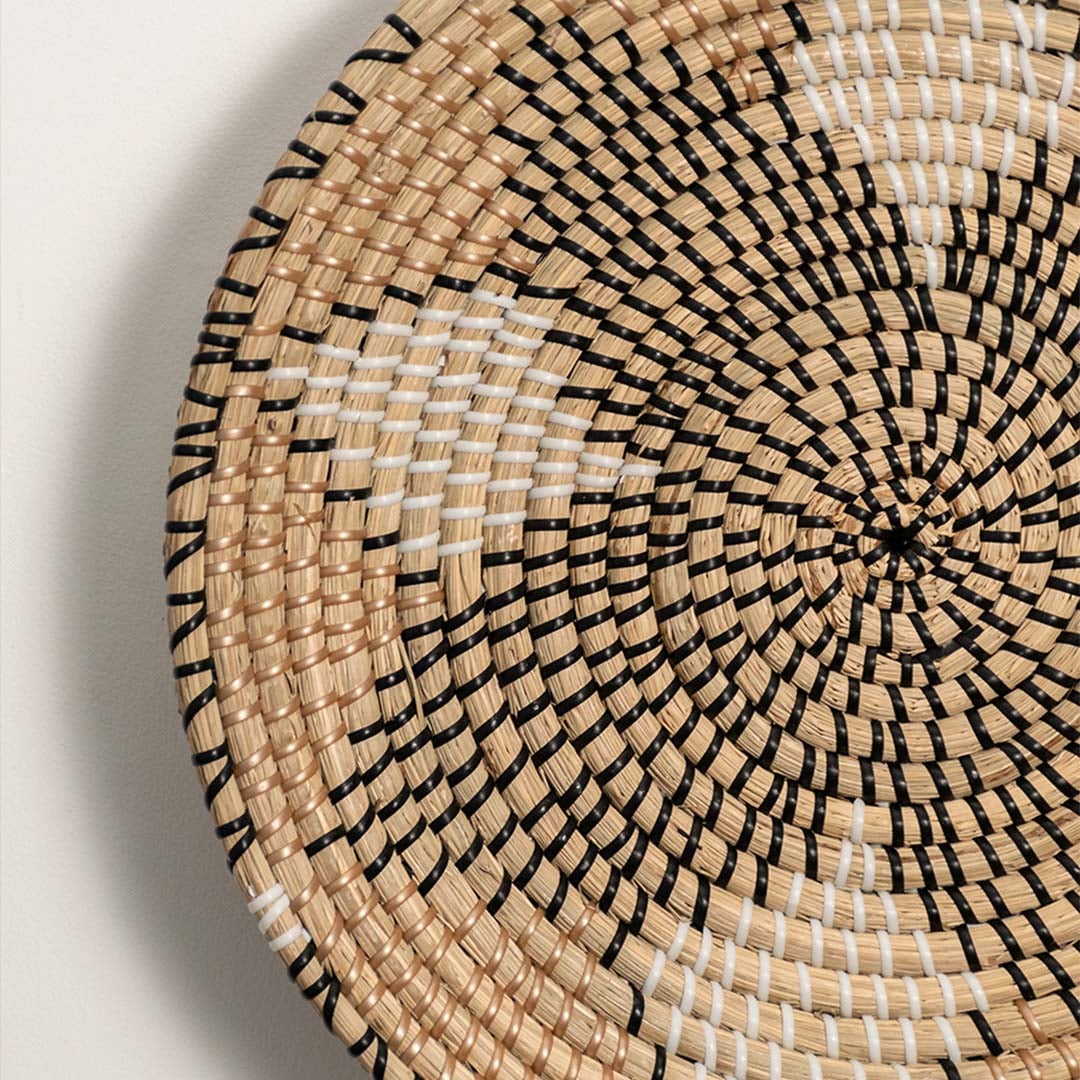 Closeup of handwoven wall basket showing natural fiber spiral pattern with beige tones highlighting artisan texture and decor detailing.