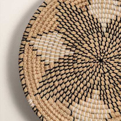Closeup of handwoven wall basket showing natural fiber spiral pattern with beige tones highlighting artisan texture and decor detailing.