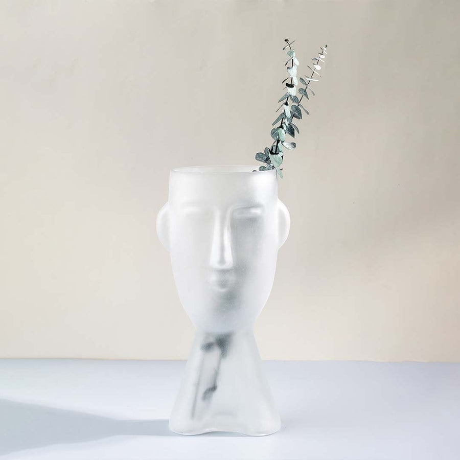 Frosted glass vase in abstract face design tall artistic decor piece matte white finish light on white background for home interiors.