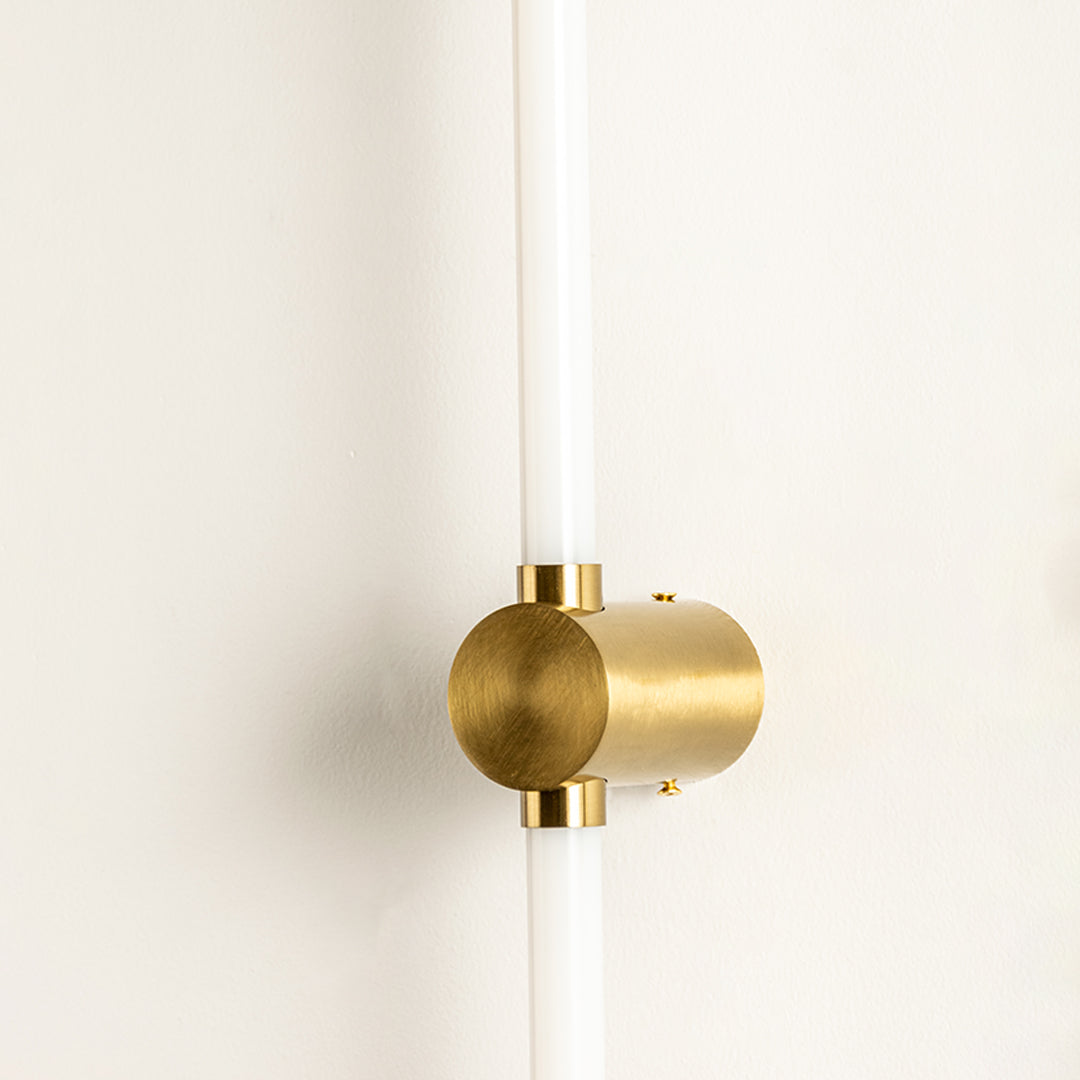 Closeup of wall light with gold metal cylindrical mount and tube design showcasing premium finish for modern interior decor styling.