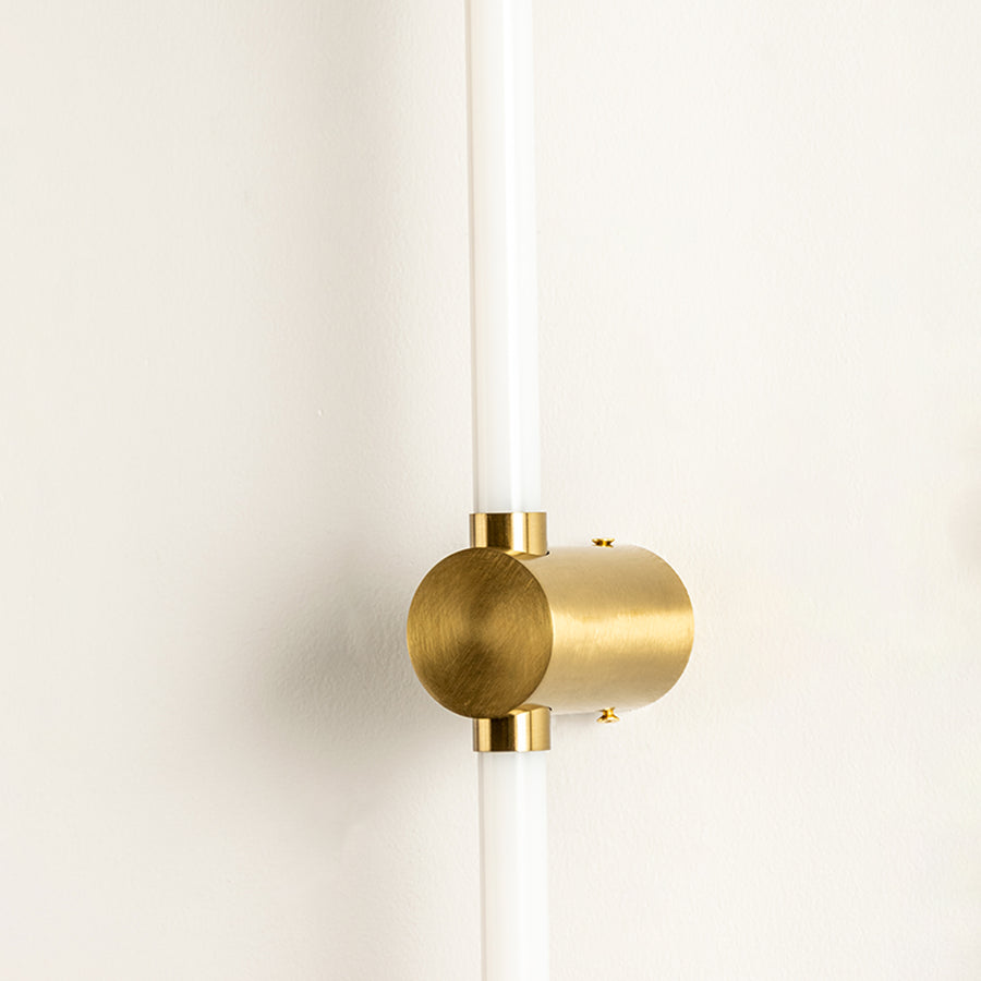 Closeup of wall light with gold metal cylindrical mount and tube design showcasing premium finish for modern interior decor styling.