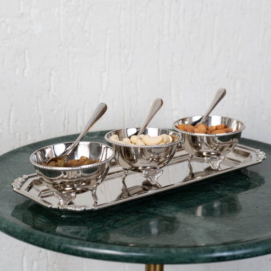 Silver bowl with spoon shown separately featuring round feet and beaded rim placed on white surface background.