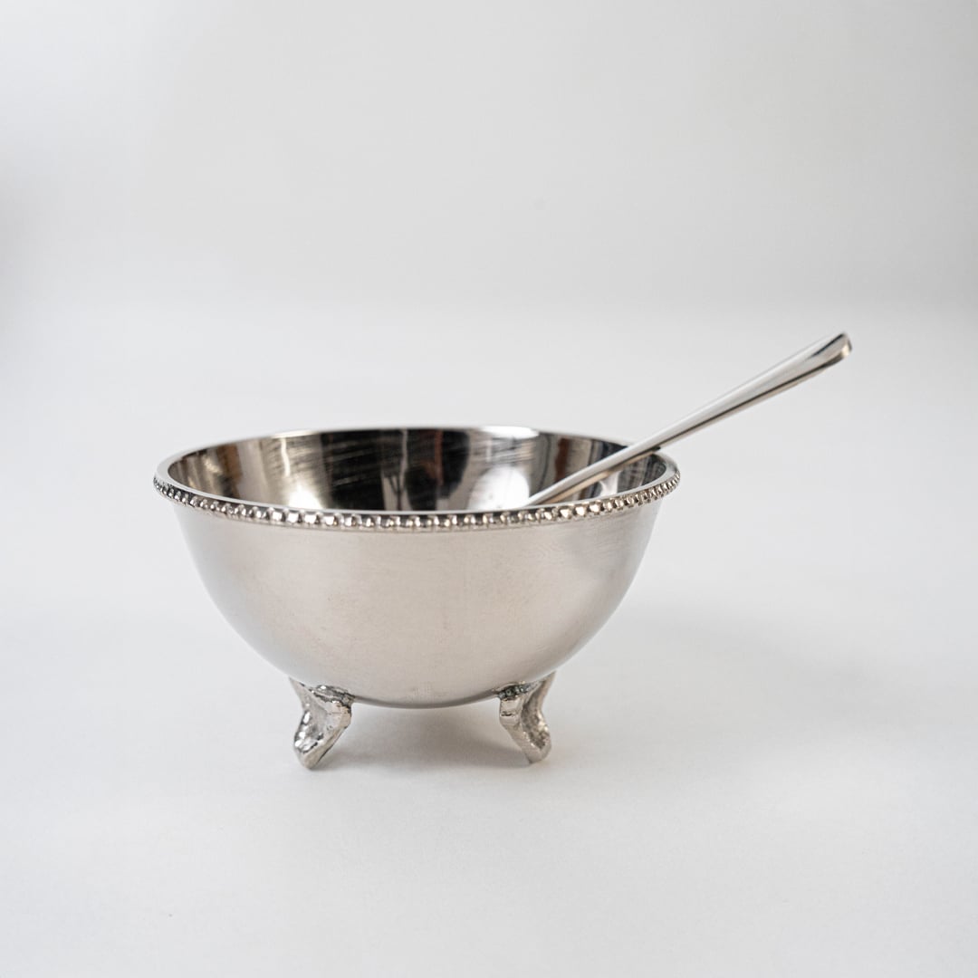 Elegant silver tray set with bowls and spoons partially shown inside open black gift box with gold branding.