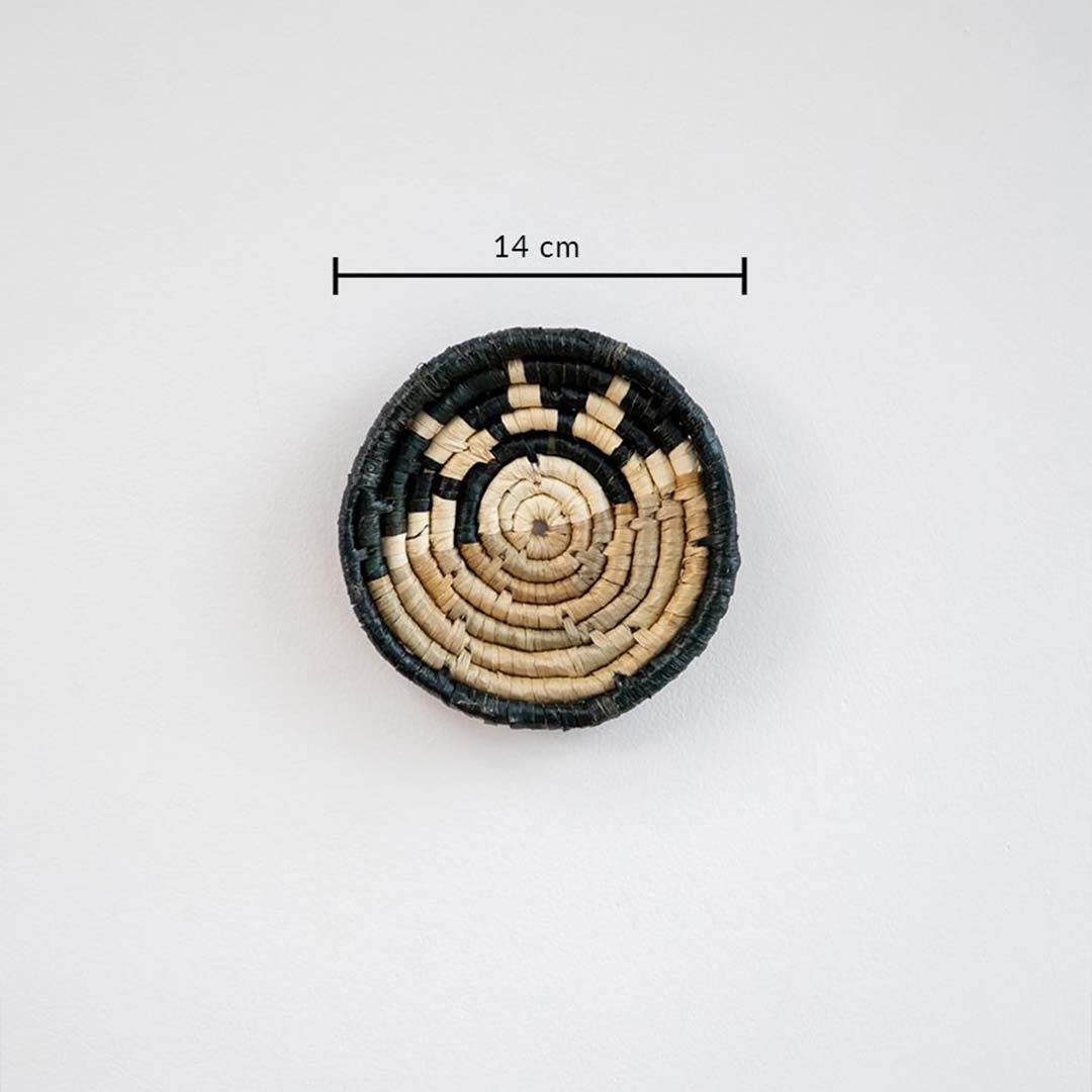 Handwoven round wall basket in black and natural fiber showing approx 25 cm diameter for accurate interior wall decor placement.