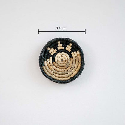 Handwoven round wall basket in black and natural fiber showing approx 25 cm diameter for accurate interior wall decor placement.