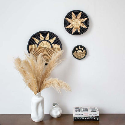 Black and beige bamboo wall plates displayed above wooden table with white vase adding rustic elegance to home decor.