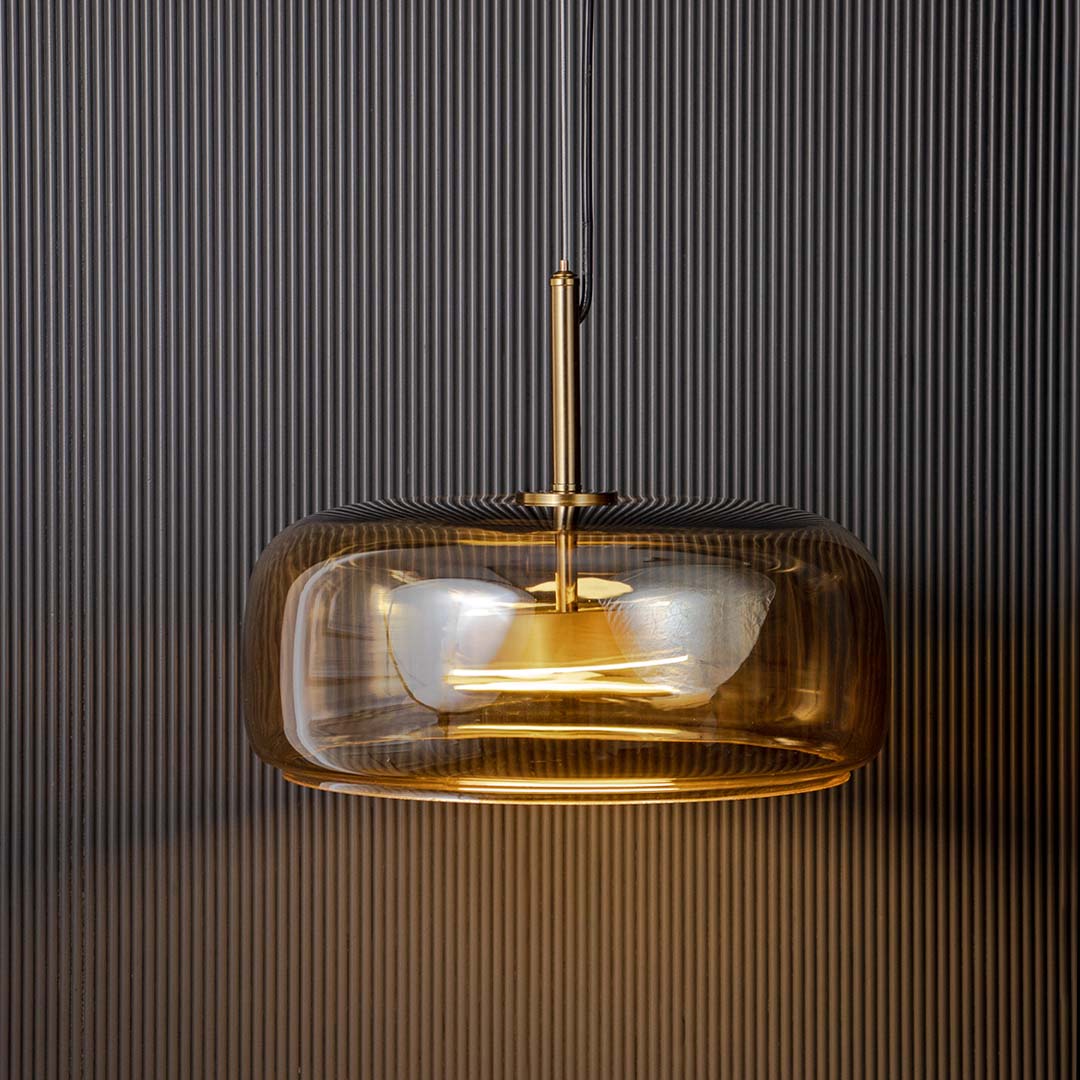 Closeup of amber glass pendant light with brass canopy showcasing premium craftsmanship details.
