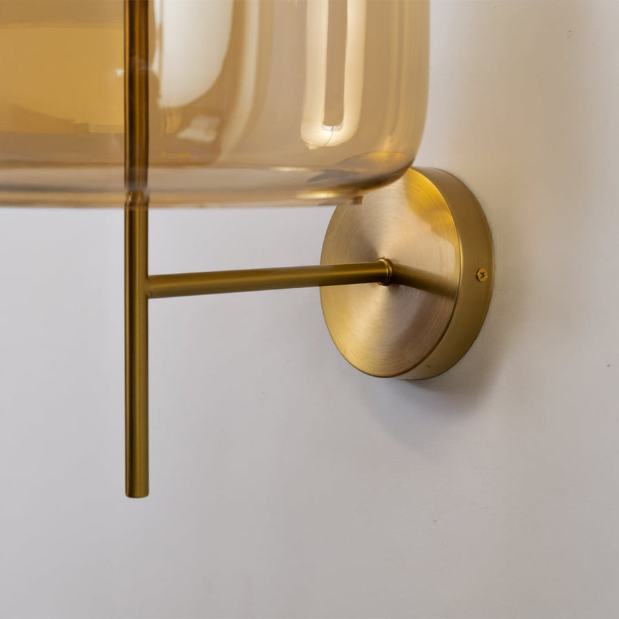 Closeup of amber glass and gold metal wall light for modern bedroom and luxury decor styling spaces.