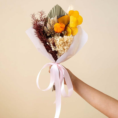 Elegant preserved flower bouquet on white background featuring orange infinity rose apple leaves hydrangea and eucalyptus.