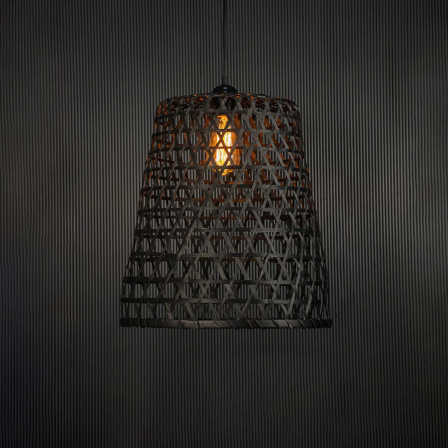 Woven bamboo pendant light glowing warmly on black background creating a cozy and elegant interior ambience.
