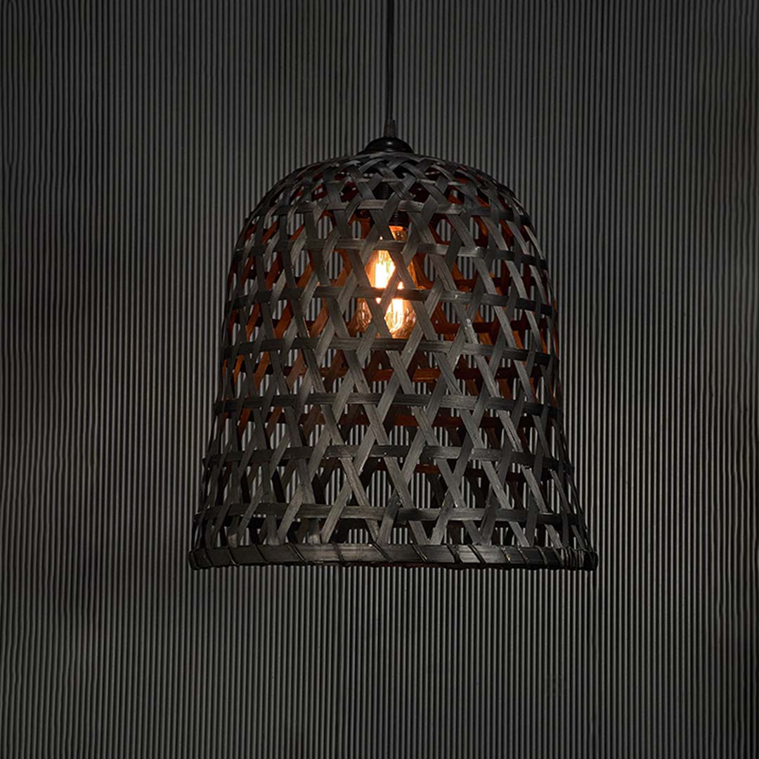 Rattan pendant light glowing warmly on black background showcasing its geometric pattern and ambient illumination.