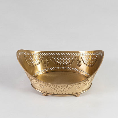 Perforated metal fruit bowl in matte gold partially packed in black luxury gift box with logo on clean white surface.