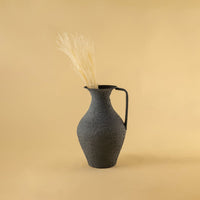 Grey metal tall jug vase decor styled in a warm modern room adding a bold elegant accent to living room tables and corner spaces.