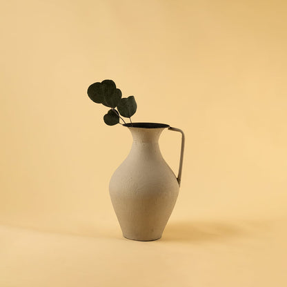 Cream metal tall jug vase placed in a cosy warm setting creating a soft modern highlight for contemporary home interiors.