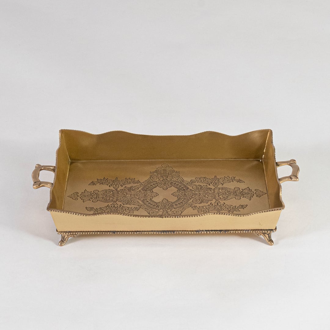 Top view of rectangular brass tray in antique gold with floral engraving and raised handles on white background.