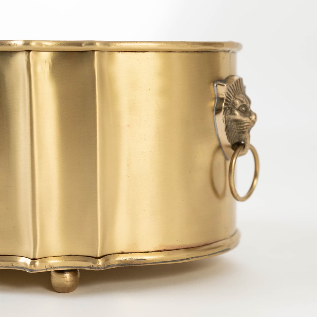 A detailed closeup of the brass fruit bowl showing the ornate engraved pattern and smooth polished finish with raised rounded feet adding a luxurious handcrafted look.
