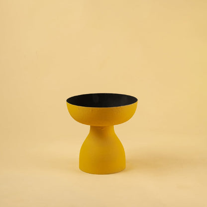Yellow pedestal bowl with black interior displayed on a clean white background for bold modern home decor styling.