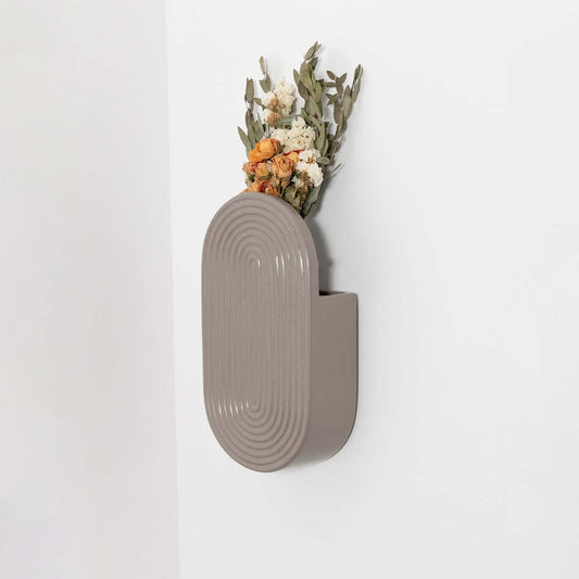 A modern wall mounted ceramic vase in a soft neutral tone styled with dried flowers adding a warm natural accent to a minimal lifestyle interior setting.