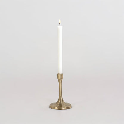 Short gold metal candle holder with sculpted base and smooth finish shown clearly on bright white background wall