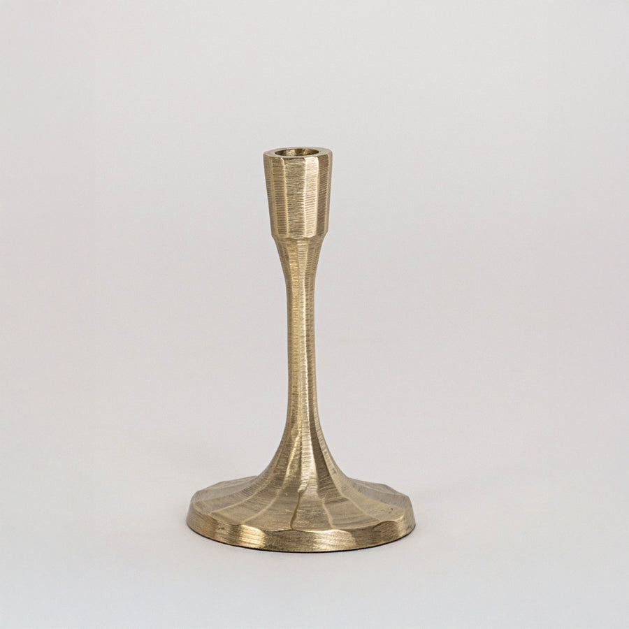 Decorative metal candle holder in gold finish with wide base for table decor or dining styling modern home placement white background.