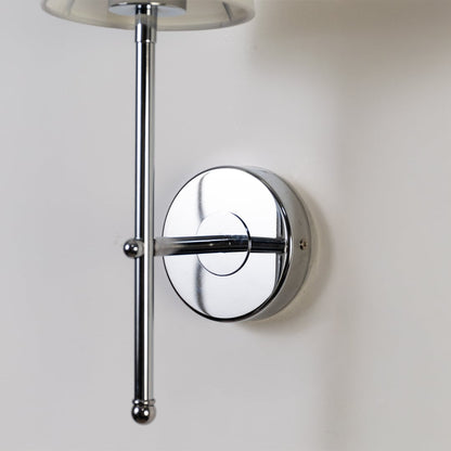 Closeup of chrome metal wall light with white fabric shade showing sleek detailing for stylish modern indoor lighting in contemporary homes.