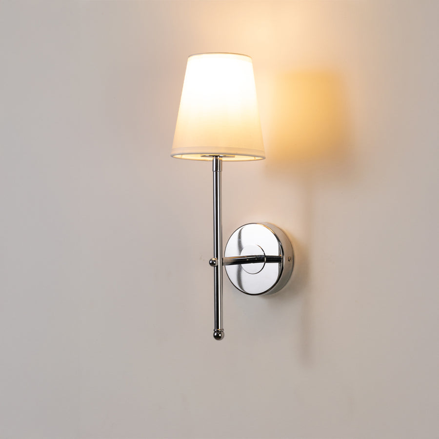 Contemporary wall light in chrome metal finish with fabric shade for bedroom or living room ambient lighting decor white background.