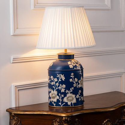 Table lamp on white background highlighting deep blue ceramic base with floral artwork and pleated shade for premium home decor styling.