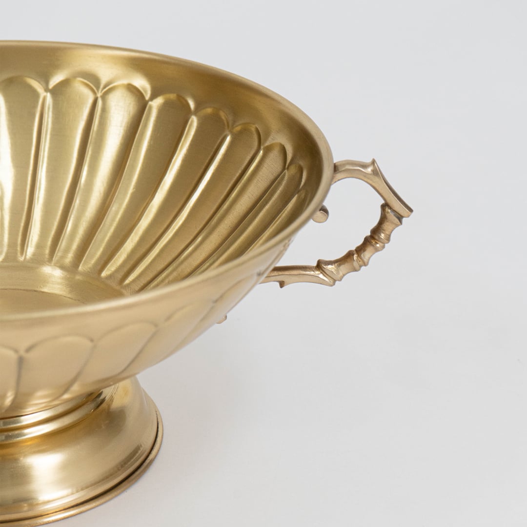 A closeup view of the golden decorative tray showing its ornate border delicate texture and raised handles with fine detailing visible across the metallic surface.