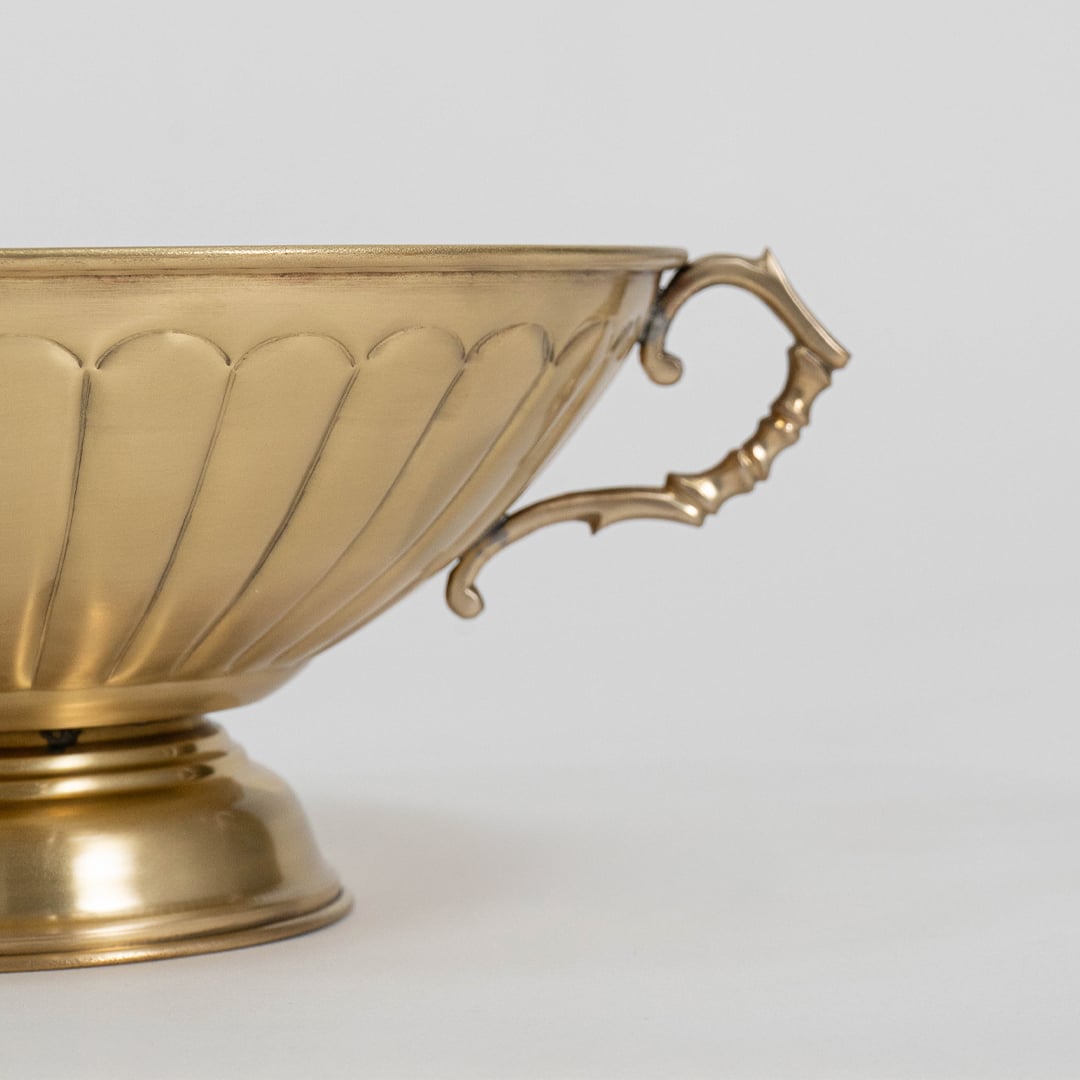 Detailed side view of antique style gold fruit bowl with fluted exterior and elegant vintage style curved handle.