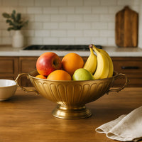 Pedestal gold fruit bowl with fluted body and no handles shown from front on clean white background for decor.