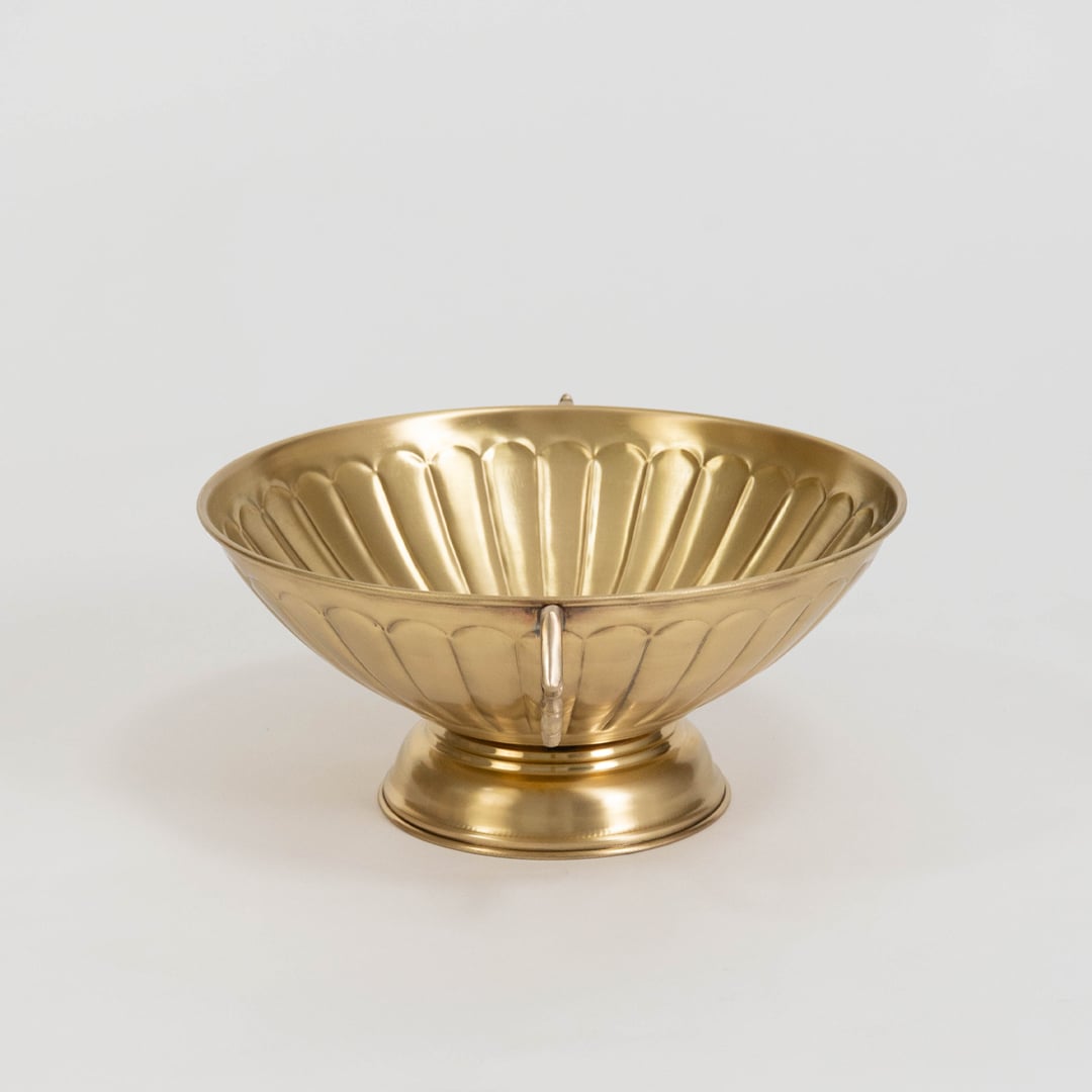 Decorative gold metal fruit bowl with twin ornate handles and fluted texture displayed on plain white background.