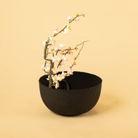 Black hammered metal bowl styled in a warm minimal scene adding bold modern texture to contemporary home decor.
