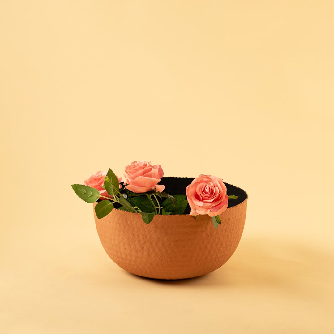 Terracotta hammered metal bowl with black interior styled in a warm neutral setup adding earthy modern charm to decor.