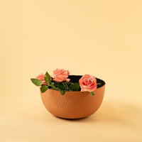 Terracotta hammered metal bowl with black interior styled in a warm neutral setup adding earthy modern charm to decor.
