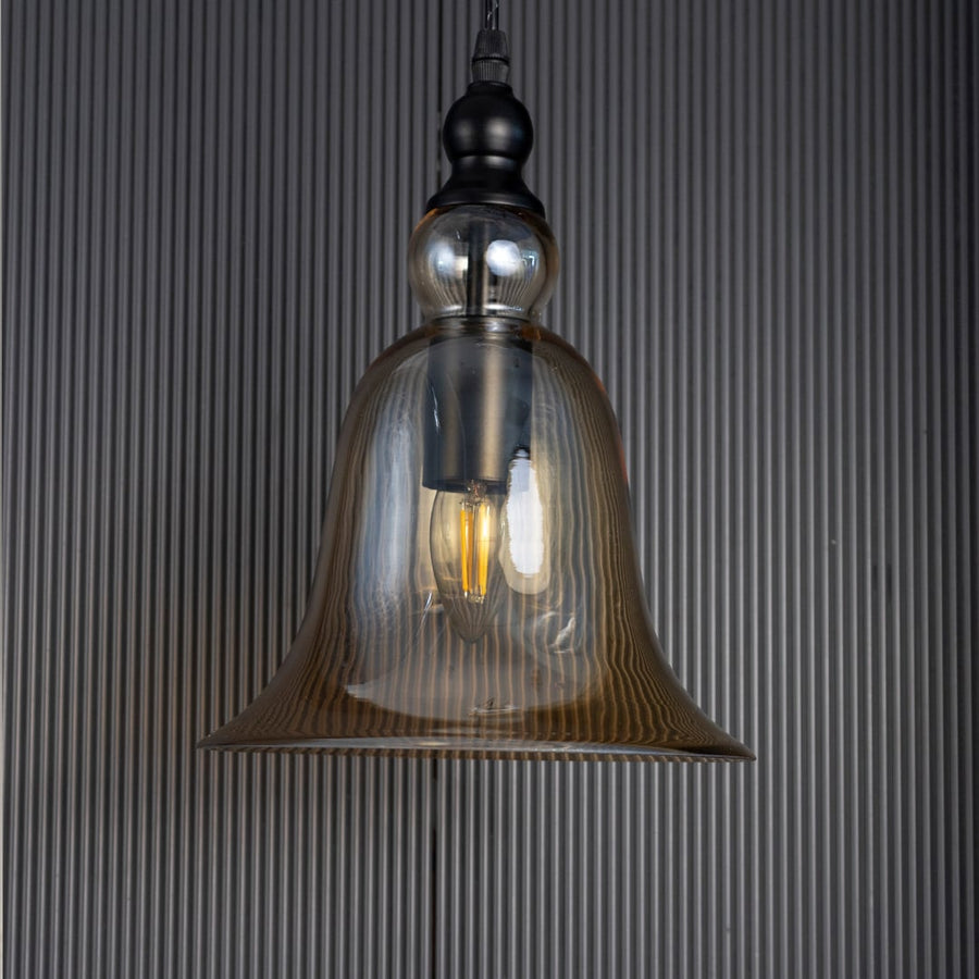 Sleek amber glass hanging light fixture turned off isolated on a pitch black background for a dramatic high contrast style.