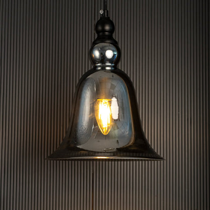 Glowing grey glass pendant lamp turned on suspended against a dark black background highlighting the warm light and bell shape.
